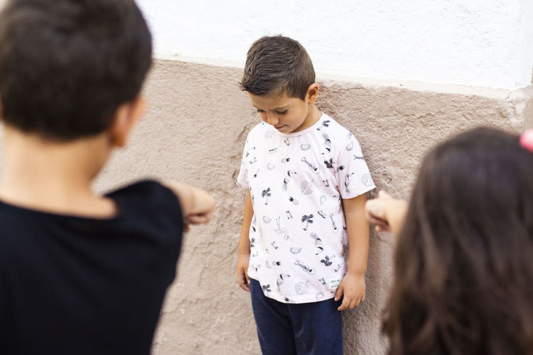Children pointing at boy against wall