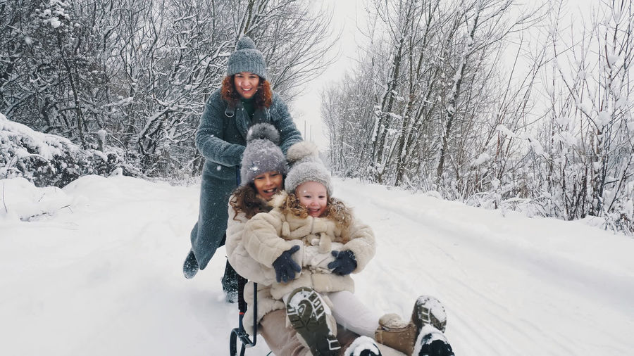 Family sledding in winter. outdoor winter activity. happy, laughing family, woman with 2 daughters 