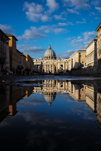 Puddle on street by st peter basilica against sky