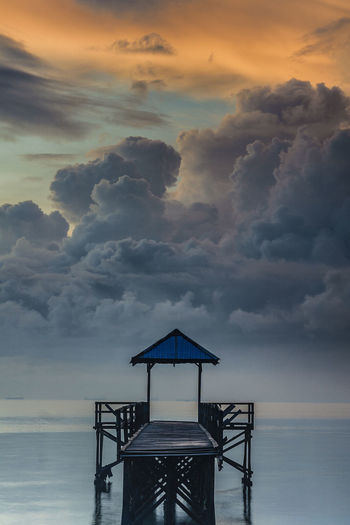 Lifeguard hut on beach against sky during sunrise