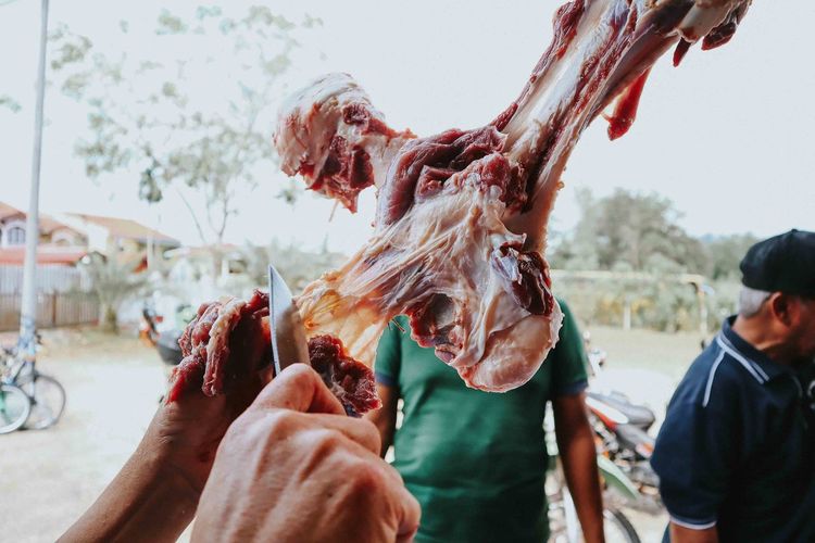 Cropped hands of man cutting meat at market stall