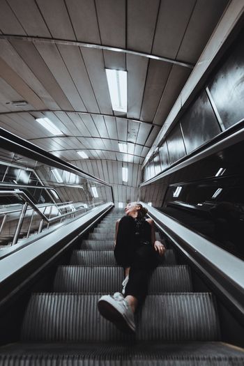 Low angle view of young woman sitting on escalator
