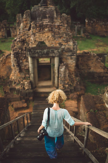 Woman walking on steps against old temple