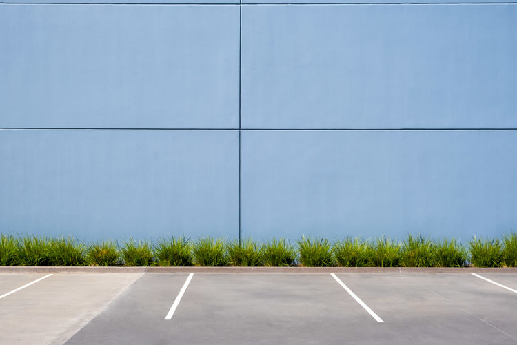 Empty parking spaces against clean concrete wall of an industrial building with copy space