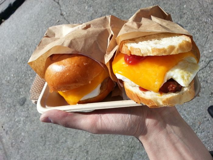Cropped hand holding burgers in plate on street