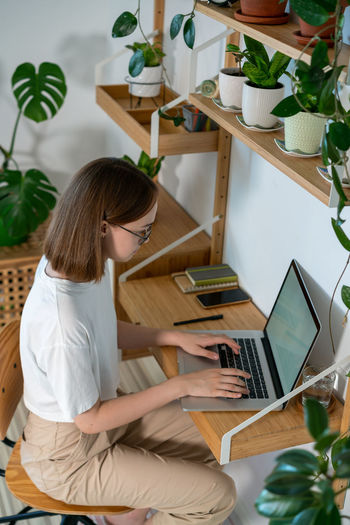 Rear view of woman using laptop while sitting on table