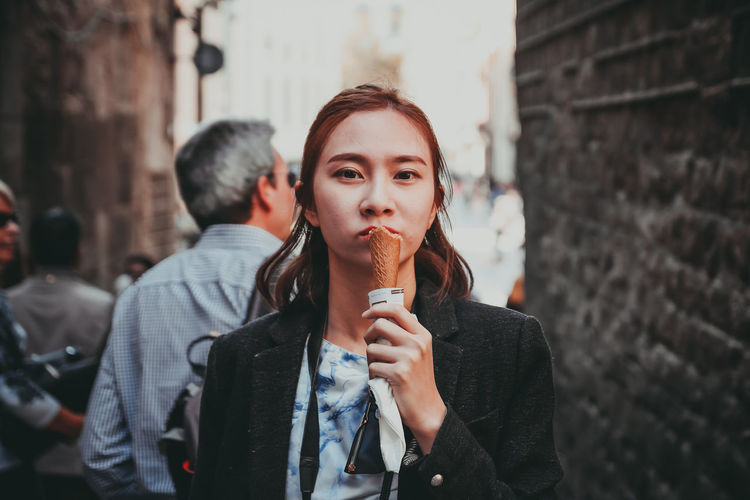 Portrait of young woman holding ice cream standing outdoors