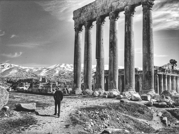 Rear view of man walking by old ruins at baalbek