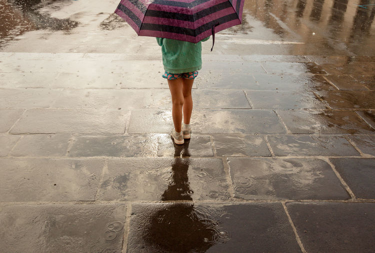 Low section of woman standing on wet footpath