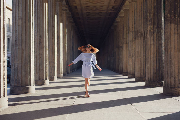 Smiling young woman walking amidst columns