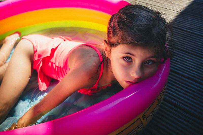 Portrait of cute girl lying in colorful wading pool