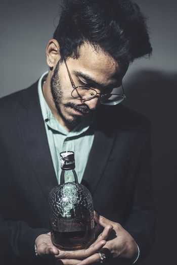 Young man wearing eyeglasses holding bottle