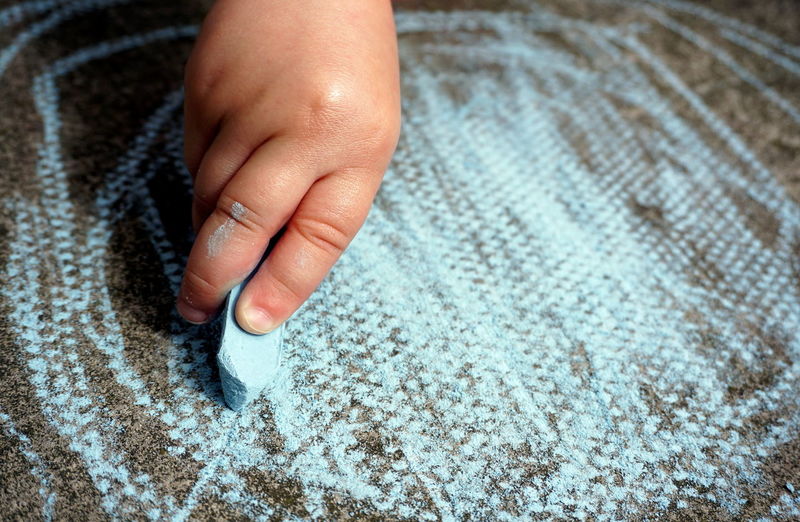 Close-up of child hand scribbling with chalk