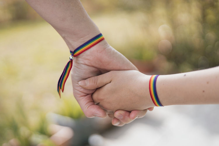 Mother and daughter holding hands with a rainbow-bracelet on their wrists