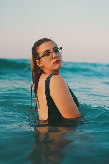 Young woman in eyeglasses at sea against sky