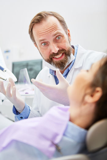 Portrait of male dentist discussing with patient at clinic