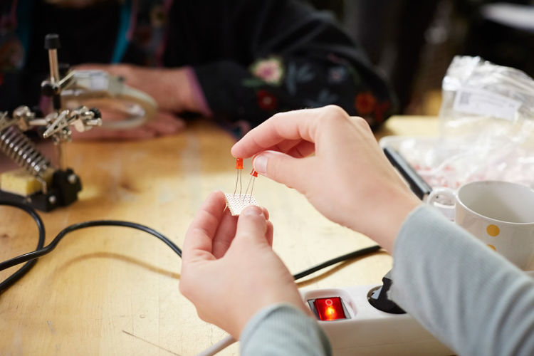 Cropped hands of young female technician holding electrical components at workshop