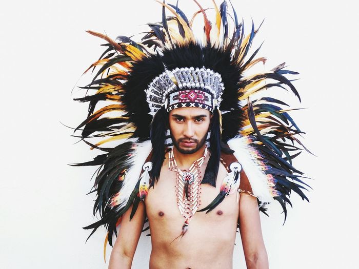 Portrait of young man wearing apache headdress against white background