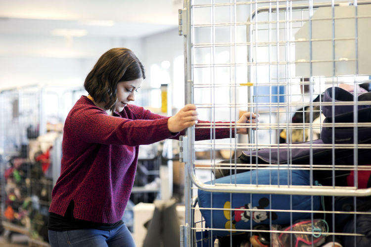 Side view of woman closing metallic gate at workshop