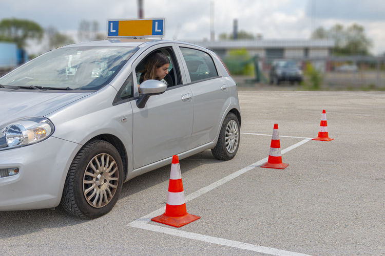Girl loooking at cones trying to orientate at parking at practise for driving test.