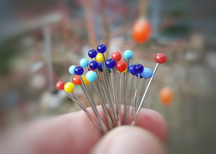 Cropped hand of person holding colorful straight pins
