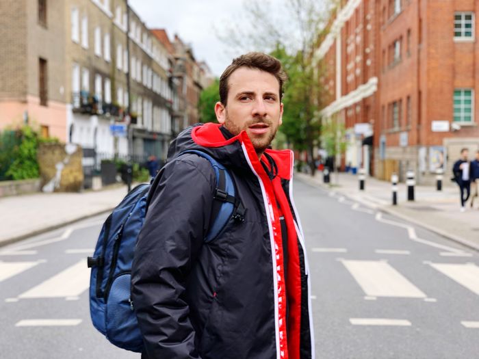 Portrait of man standing on road in city