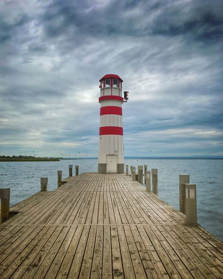 Lighthouse on pier over sea against sky