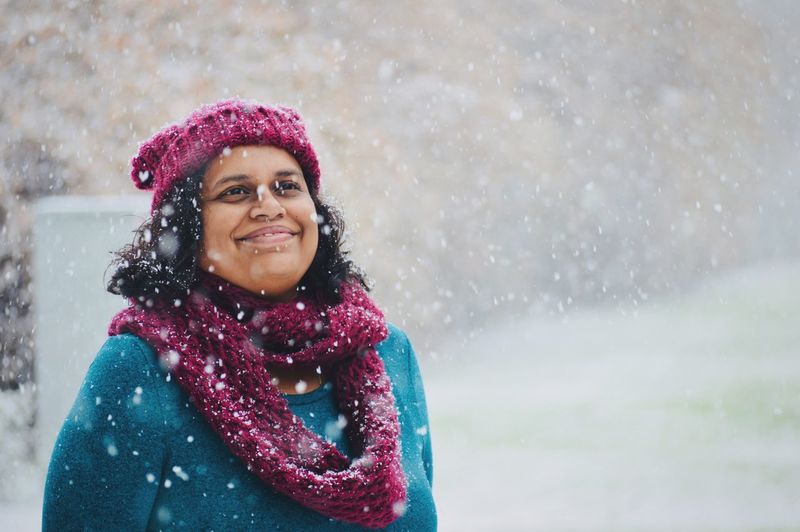 Smiling woman standing outdoors during snowfall