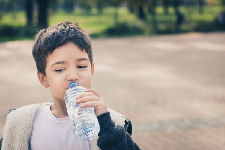 Close-up of boy drinking water while standing at park