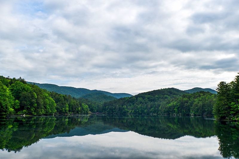 Scenic view of lake and forest against cloudy sky