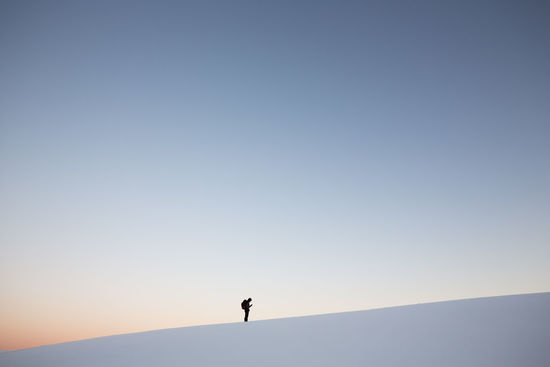 Man standing on snowcapped mountain against clear sky at sunset