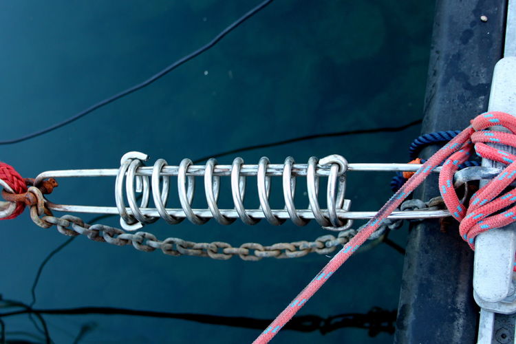 Coiled spring and ropes attached to cleat at harbor