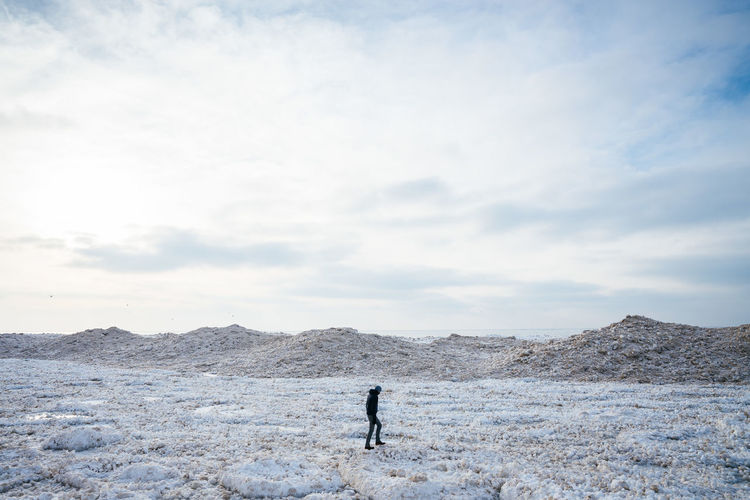Man standing on snow covered land against sky