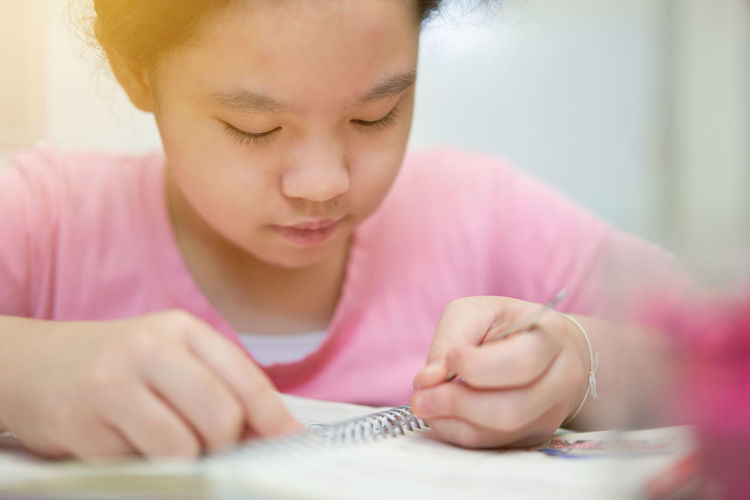 Close-up of girl drawing on book at home