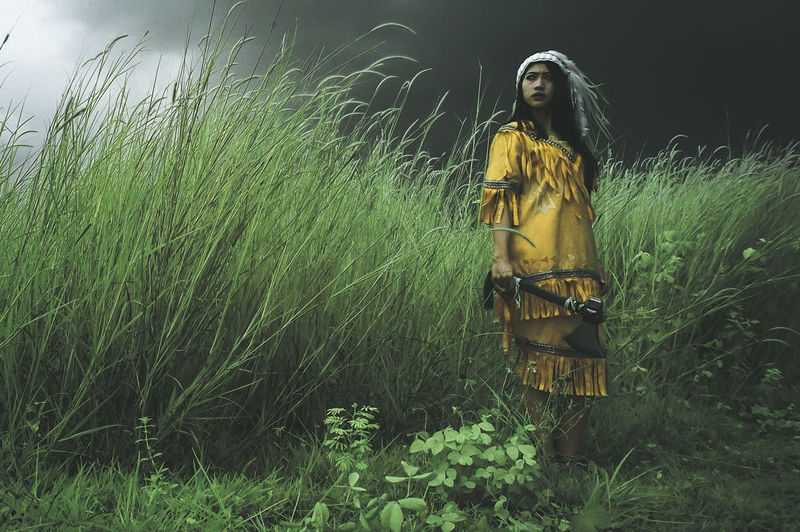 Young woman standing on field against sky at night
