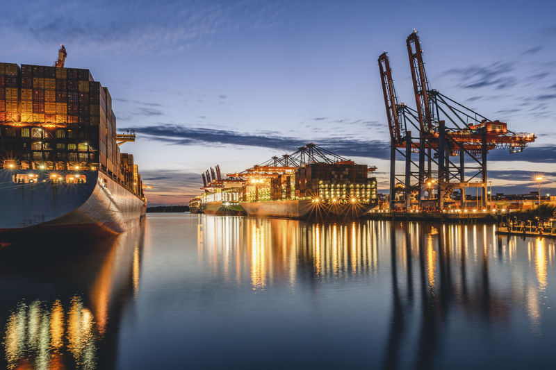 Germany, hamburg, container ships in port of hamburg at dusk