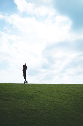 Woman standing on golf course against sky
