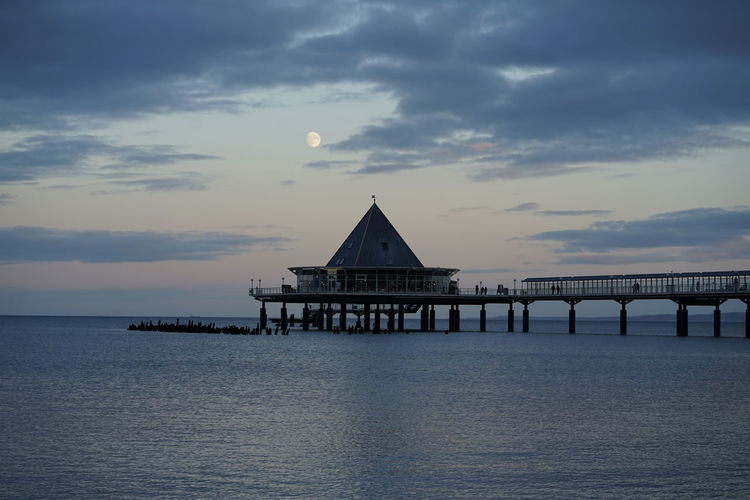 Pier over sea against sky during sunset