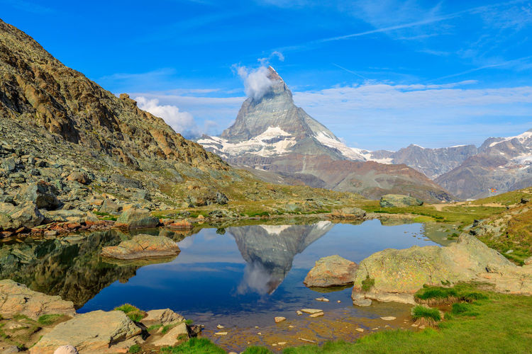 Scenic view of lake and mountains against blue sky