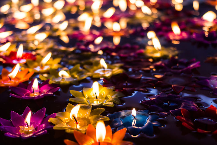 Close-up of illuminated flower candles on pond