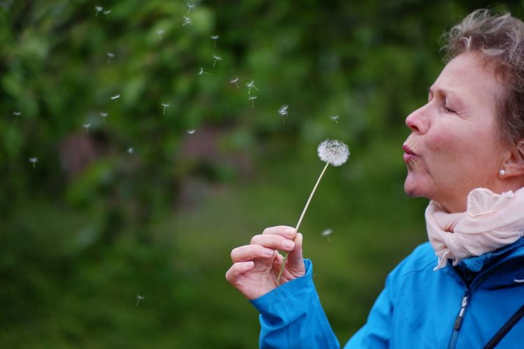 Woman blowing dandelion outdoors