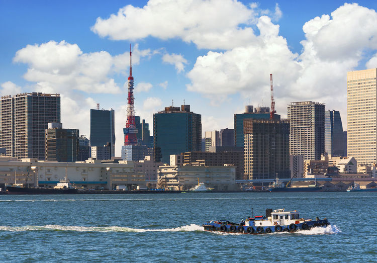 Japanese tugboats sailing in front of the hinode pier on tokyo port with tokyo tower.