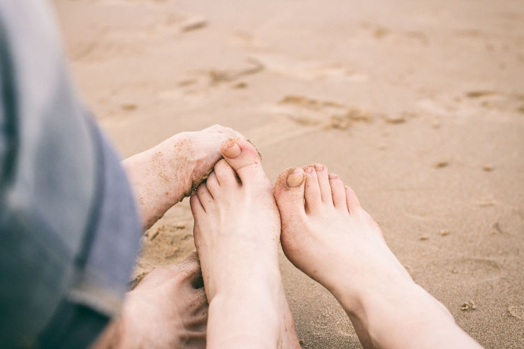 Low section of couple sitting on sand