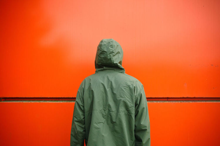 Rear view of man standing against orange wall