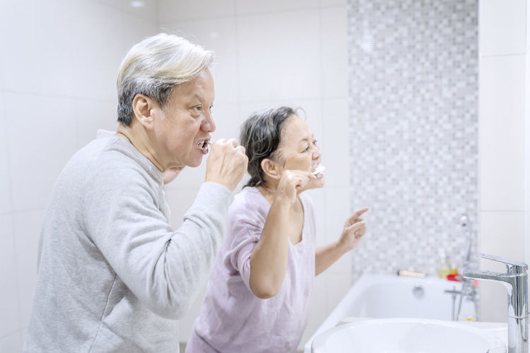 Senior couple brushing teeth in bathroom