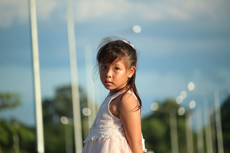 Portrait of girl standing against sky