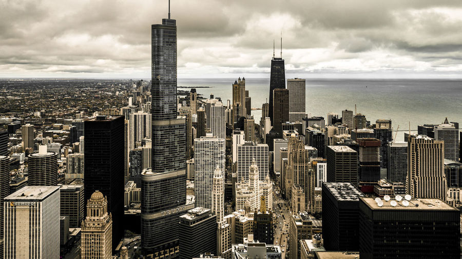 Willis tower in city by sea against cloudy sky