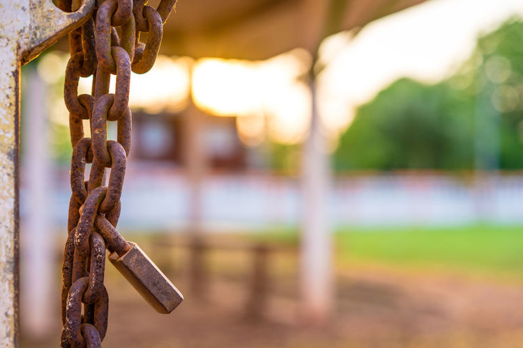 Close-up of rusty padlock hanging on chain