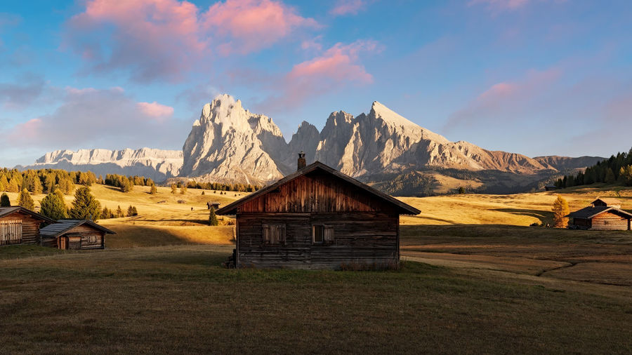 House on field against mountains during sunset