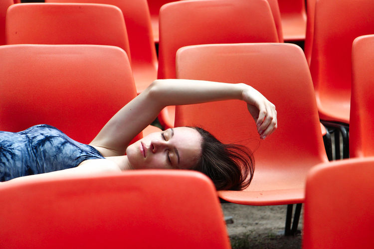 Young woman sleeping on red chairs